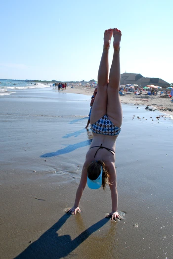 a person on a beach doing a handstand with their feet in the air