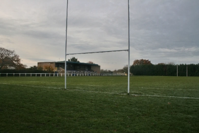 a grassy field with a soccer goal and goal posts in front of an empty stadium