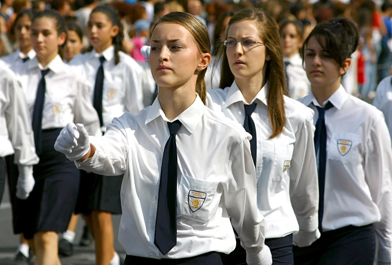 several school girls wearing uniforms and ties are marching