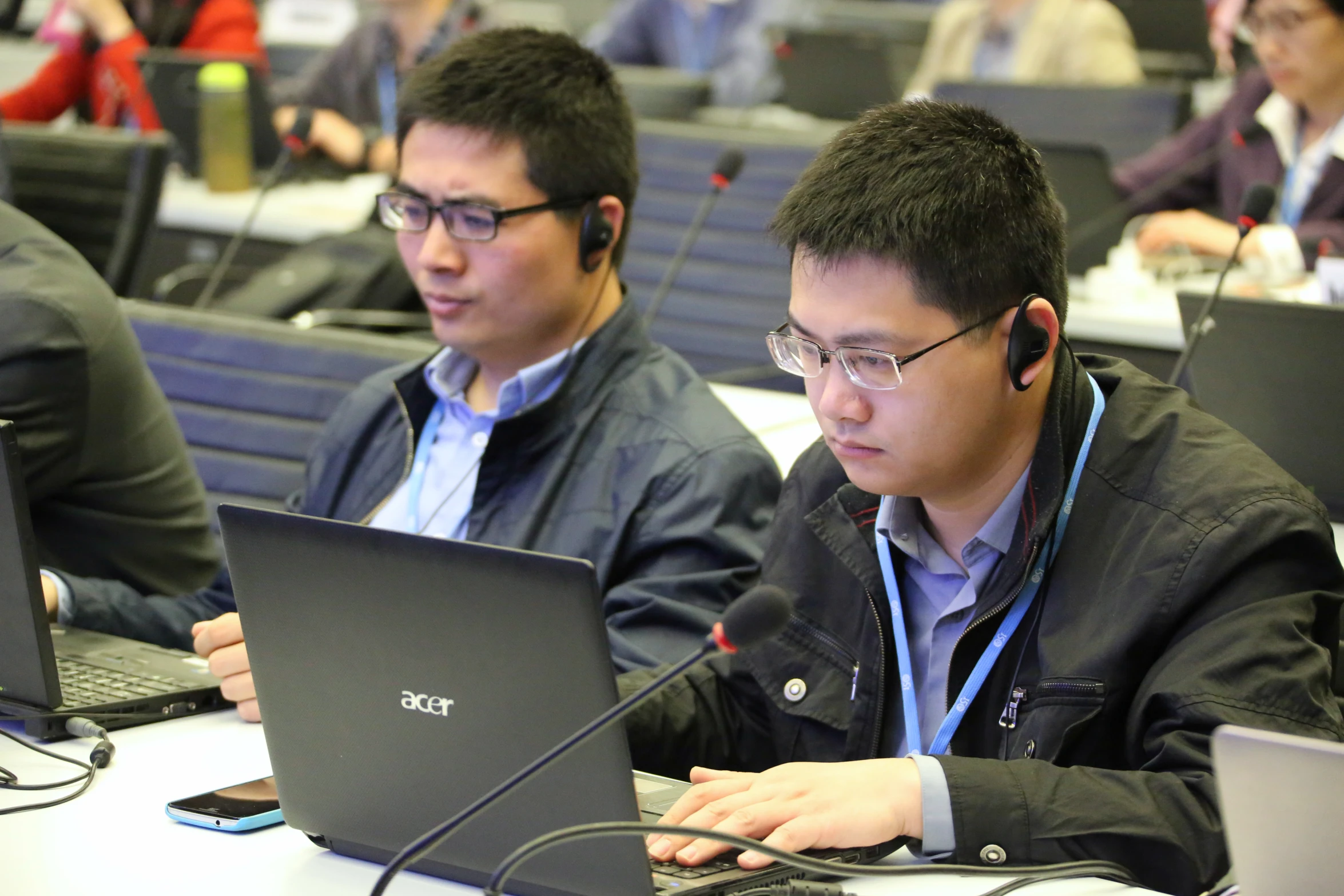 three young men are at tables working on laptops