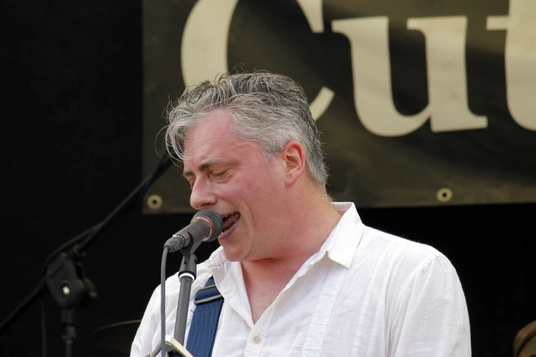 a man with grey hair standing in front of a microphone