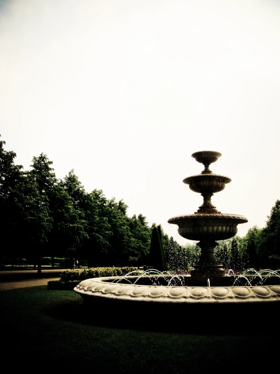 a water fountain in a park with trees in the background