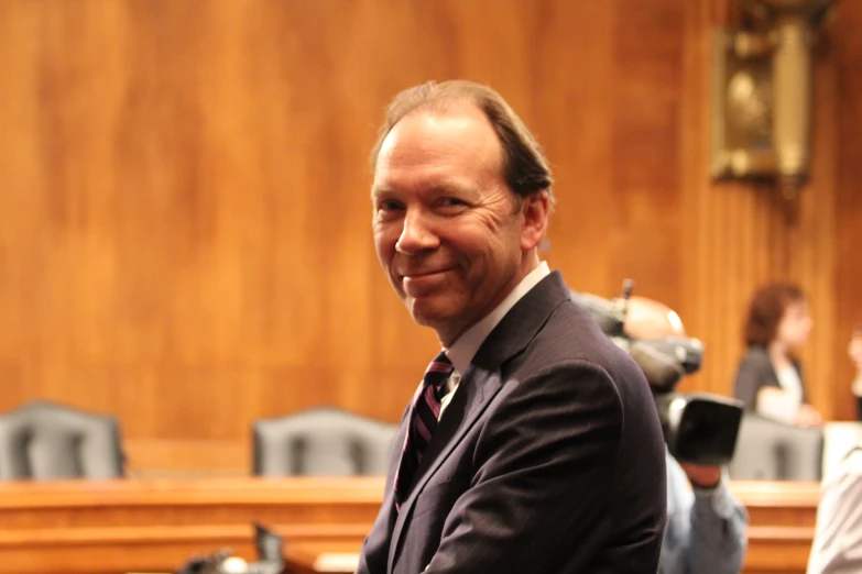 the man smiles at a microphone in the courtroom