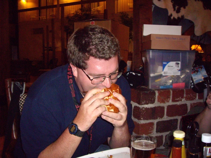 a man sitting at a table with a large sandwich in his hand