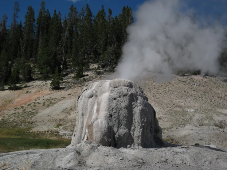 a steam rising from a large rock on top of a field