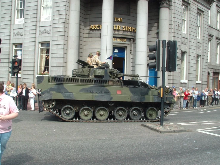 a tank is going through an intersection while people watch