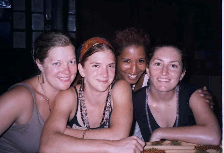 four girls are sitting at a table posing for the camera