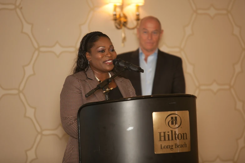 woman singing into a microphone while standing in front of a man