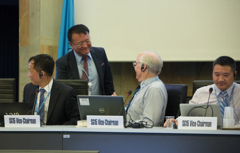 three men sitting at a table with laptops