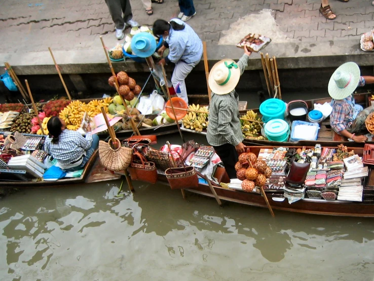 the men are selling their goods on the boats in the water