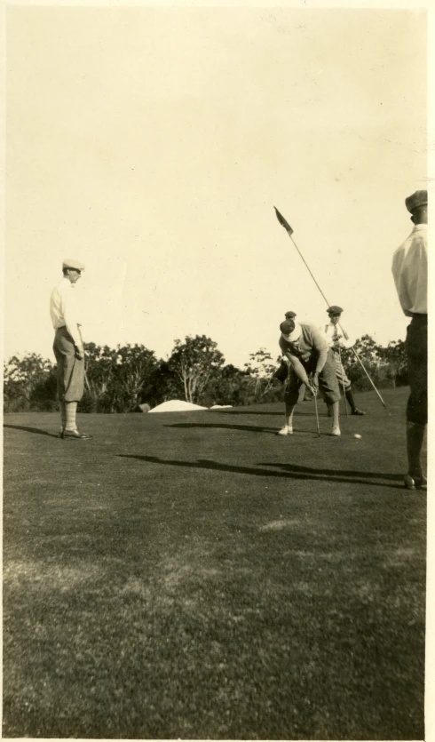 a man in military uniforms holds his putter while another man watches from behind