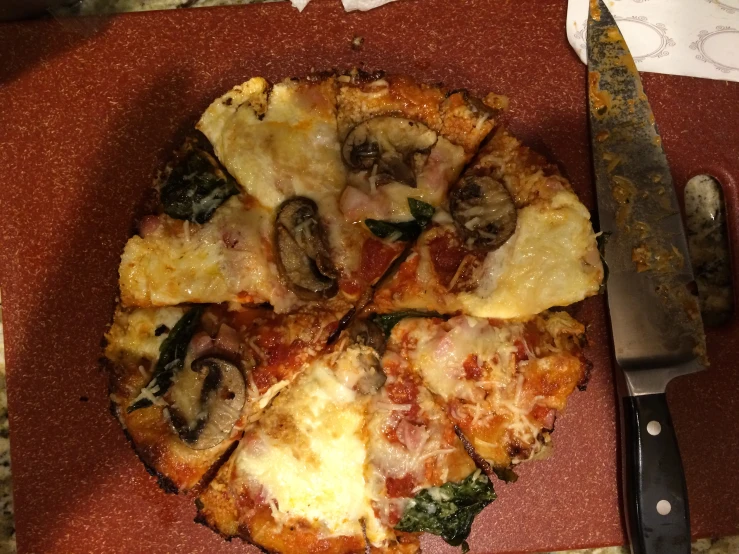 a close up of a sliced pizza on a red  board