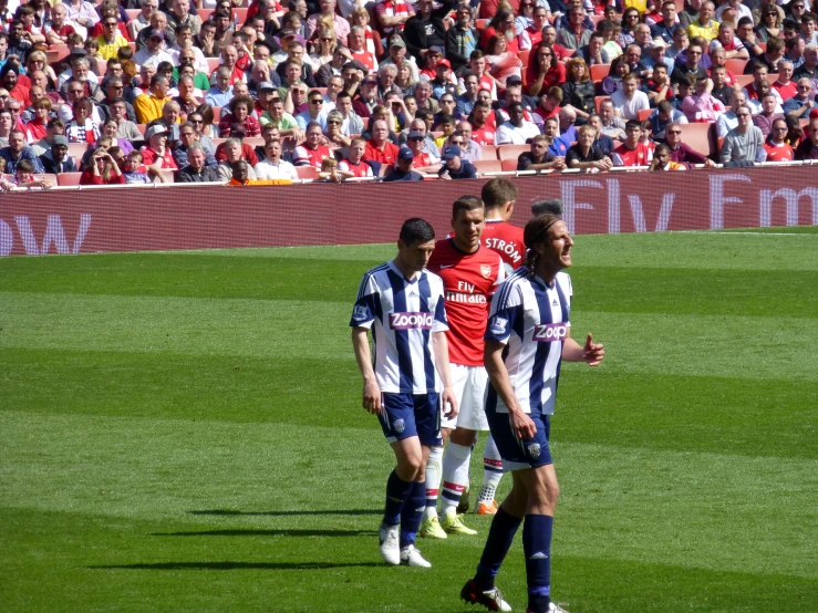 two men playing soccer on a field with an audience