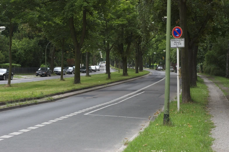 some cars driving down the street by some trees