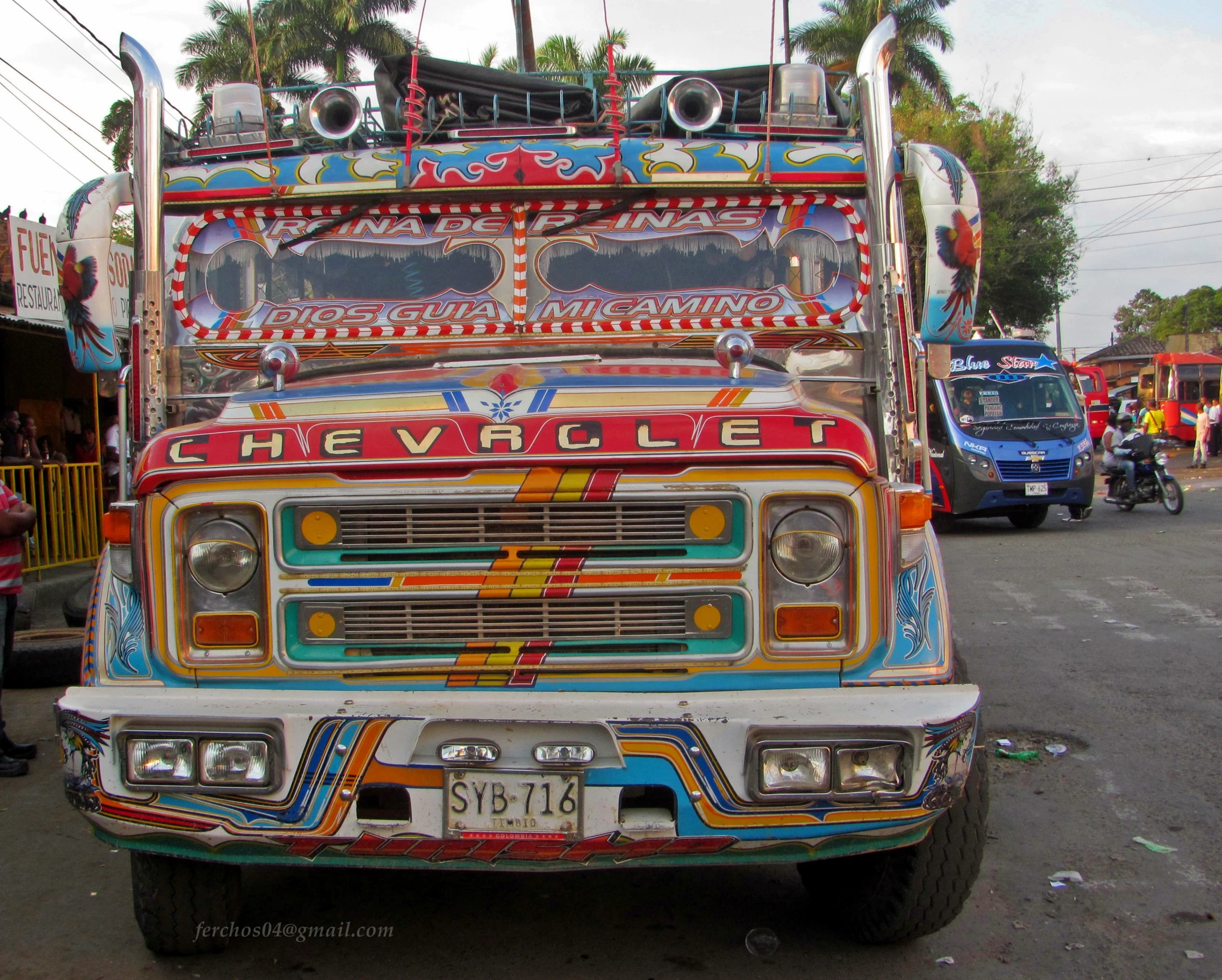 a brightly colored truck is parked next to other buses