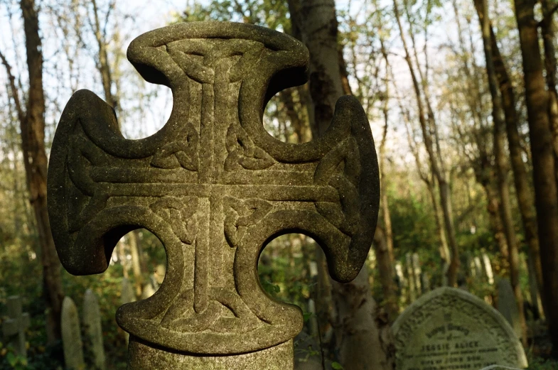 a stone cross in the middle of a cemetery