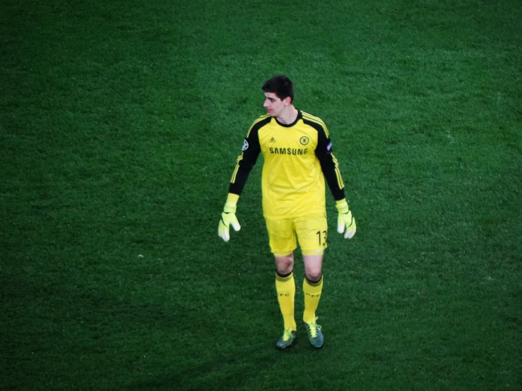 soccer player on grass looks down with hands clasped