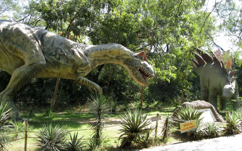 two dinosaurs walk on a grassy area between some trees