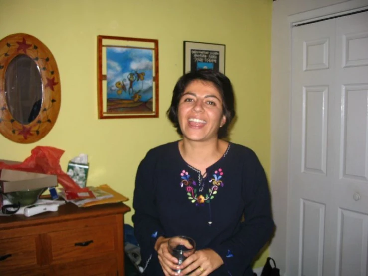 woman standing by yellow wall holding a glass