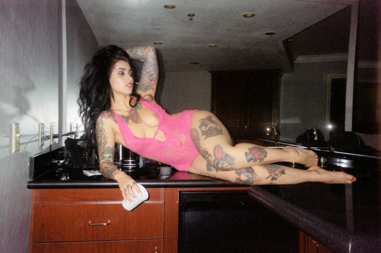 a girl with tattoos laying on a counter