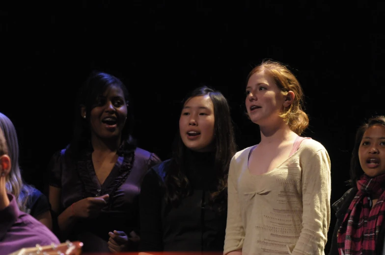 four girls standing in a row with one staring to the side