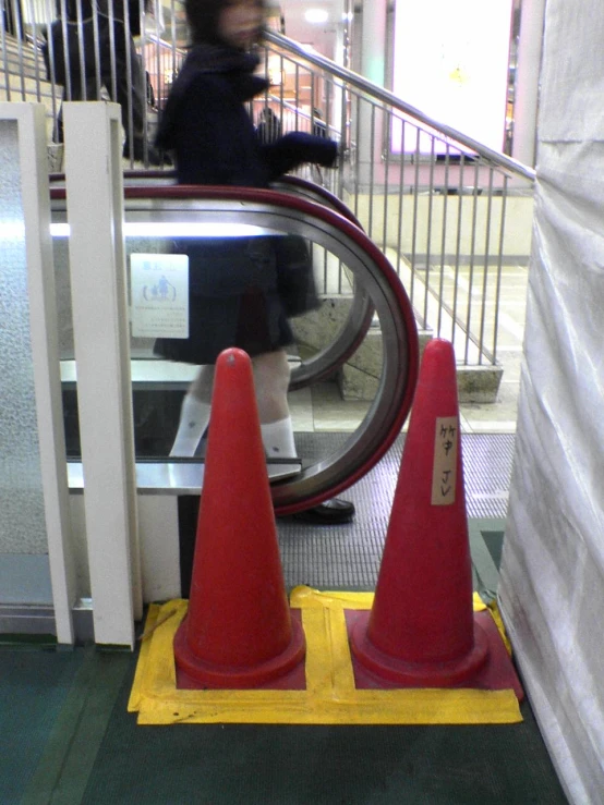 a person standing next to an escalator with three orange cones