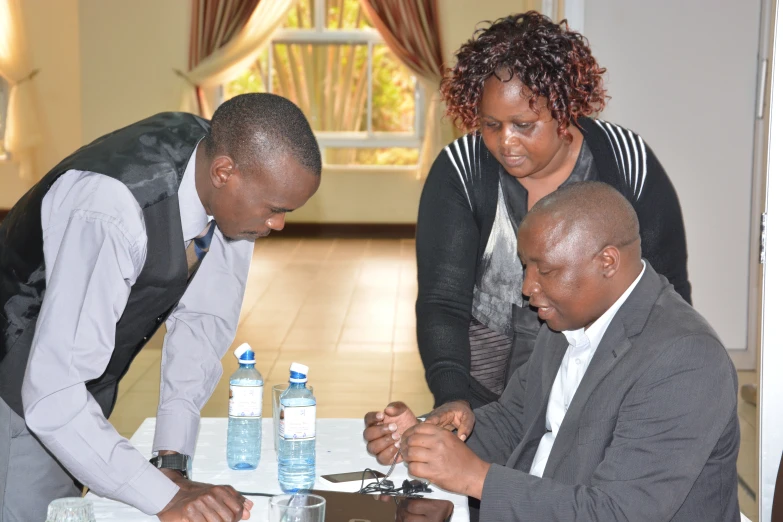 three people are gathered around a table working together