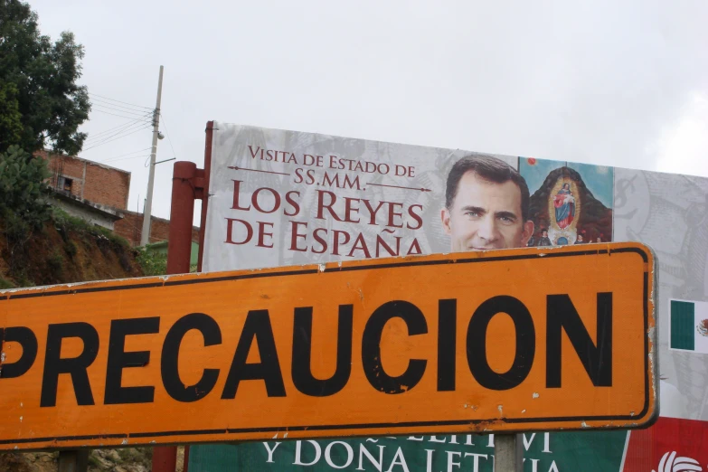 large yellow sign displayed with two posters on top