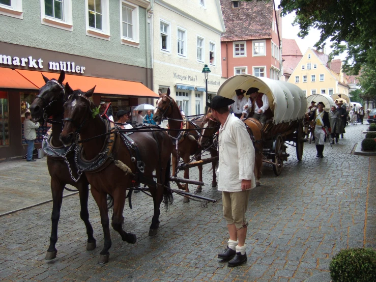 a man walking with two horse and carriage down a city street