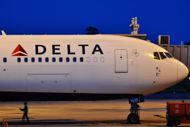 a delta airlines airplane at an airport with people walking around it