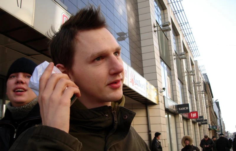 a man is on his cell phone as people walk by in the background