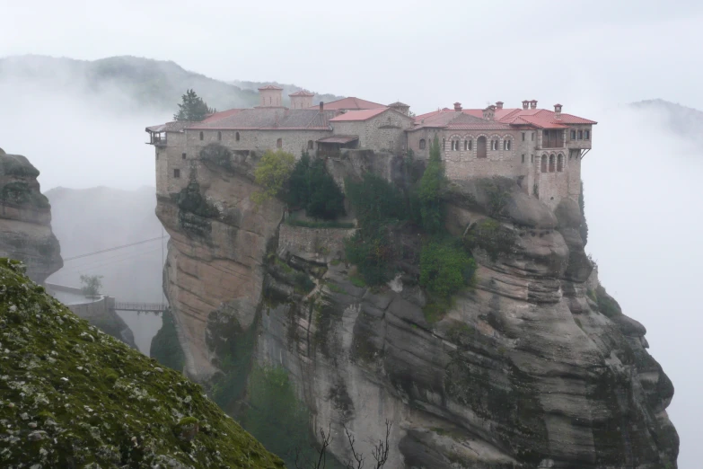 a hill with a large building and some clouds in the air