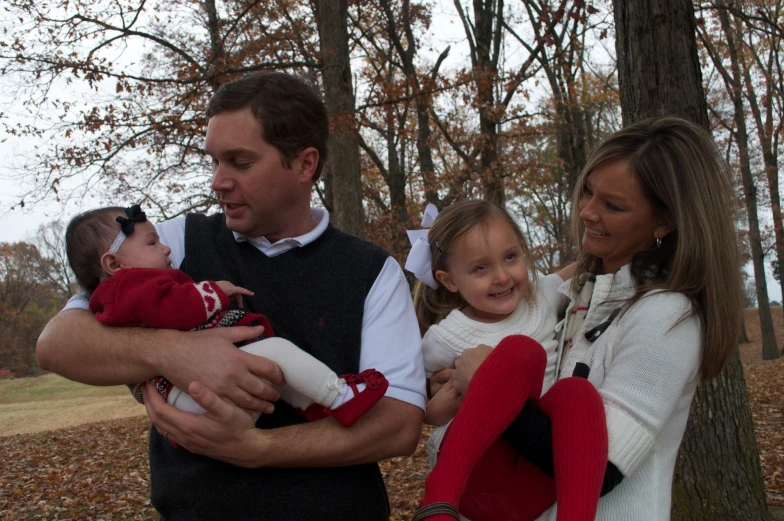 a man holding two small children near a group of people