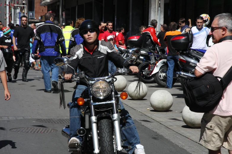 a man riding a motorcycle next to a lot of people