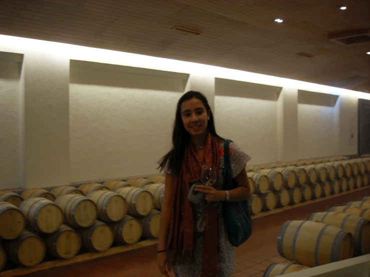 woman standing near a row of wine barrels smiling