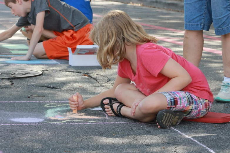 a young child draws a heart on the ground