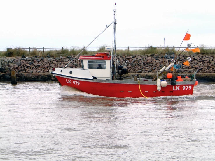 a large red boat traveling on water next to a building