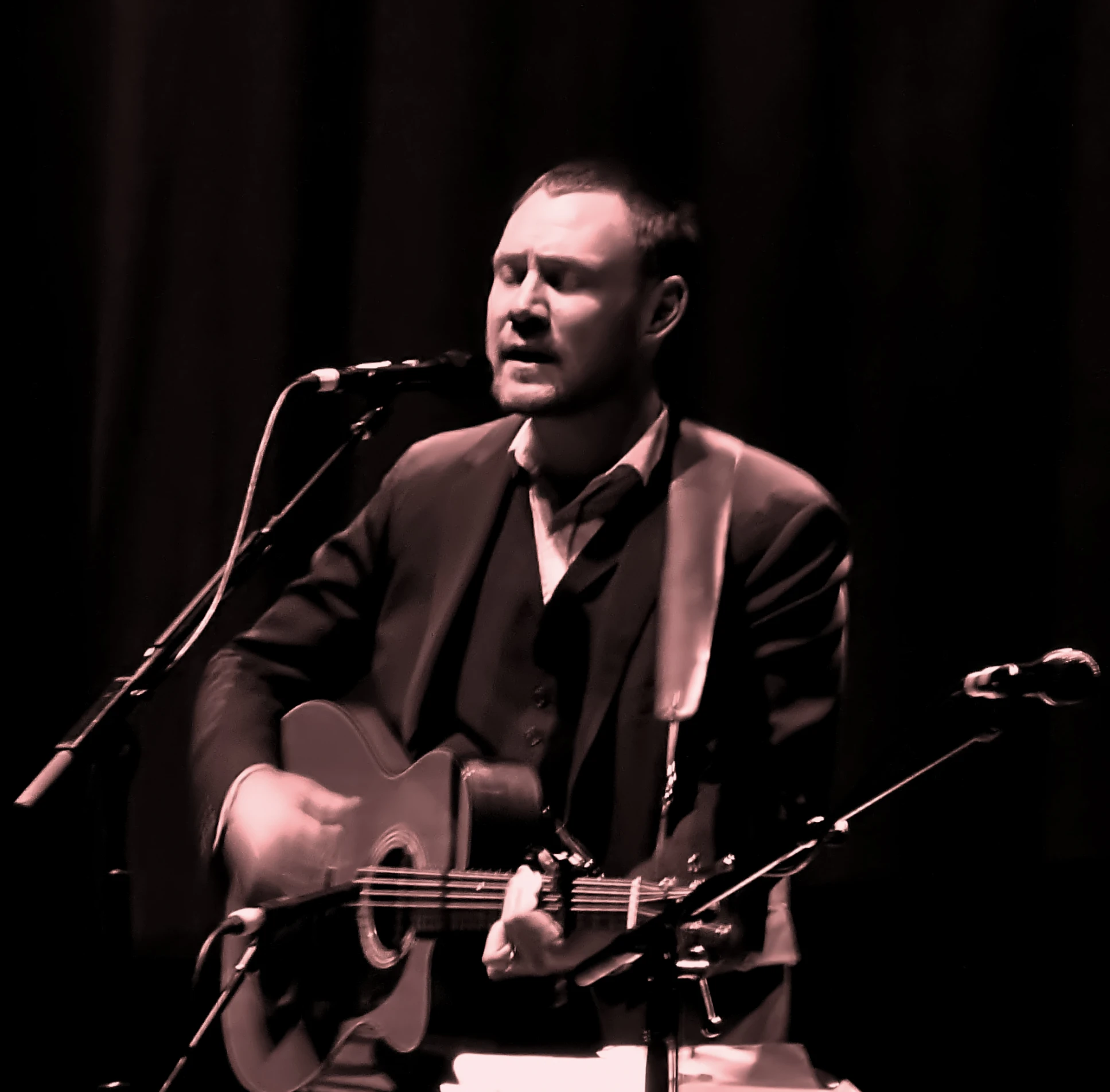 a man wearing a suit while playing a guitar