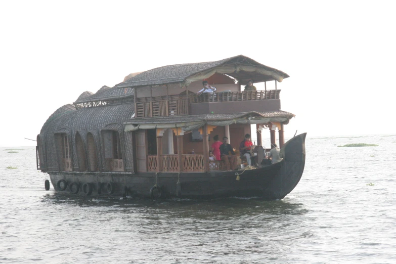 a house boat with people on top sailing through the water