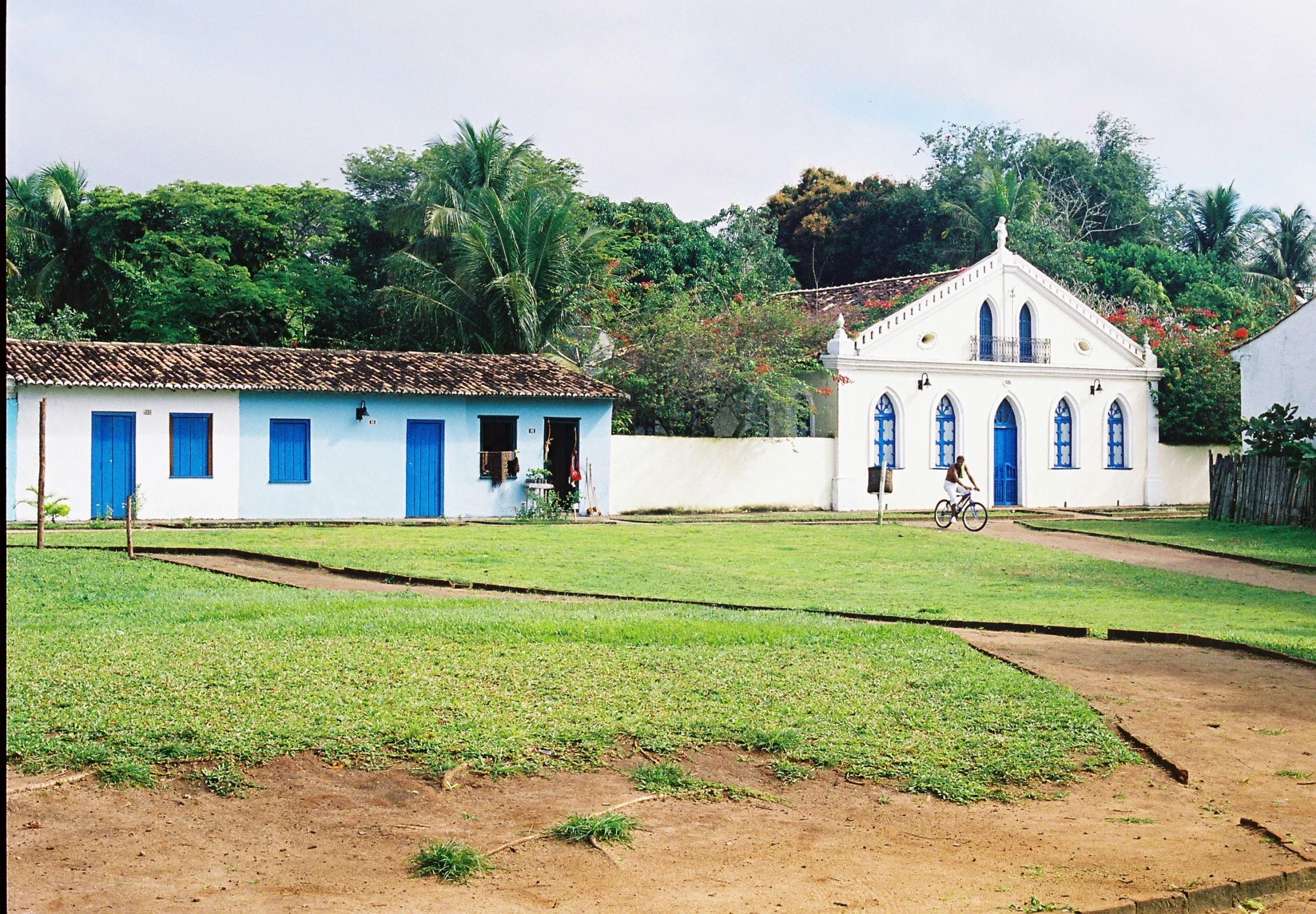 a large white and blue house sitting in the middle of a lush green field