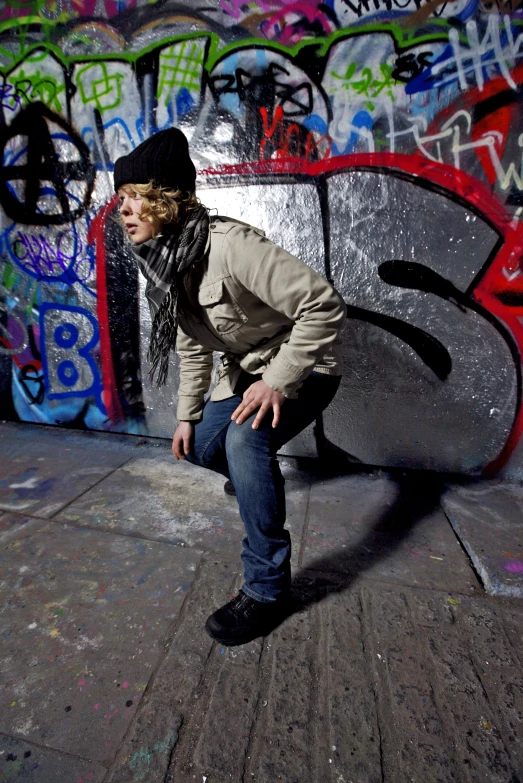 a man is leaning against a wall in front of graffiti