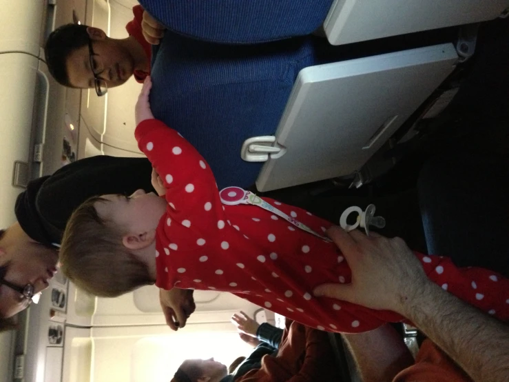 some people are sitting on the plane while one child stands near another