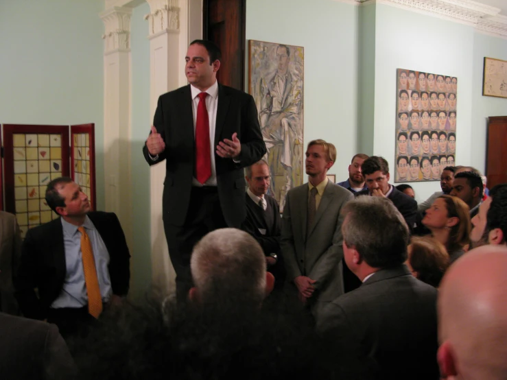 a business man standing on stage with a crowd of people behind him