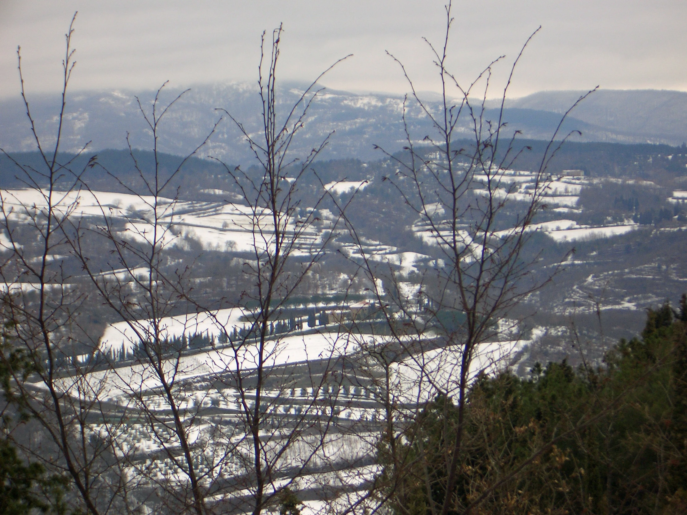 a view of the landscape covered in snow from a hill