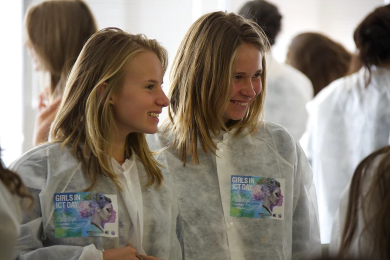 two woman are standing near each other with white coat on