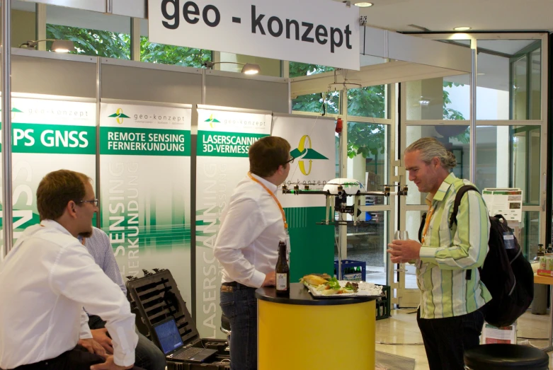 a man standing behind a counter next to two men in white shirts