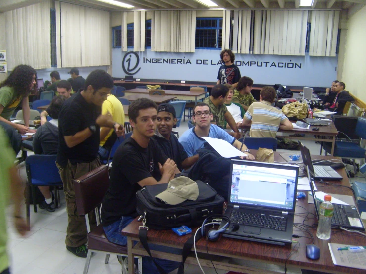 a group of men sitting around laptops in an office