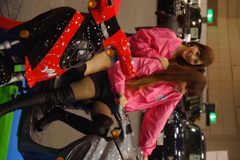 two girls in pink riding on a motorized scooter