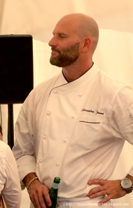 chef in a white uniform showing his company his beer