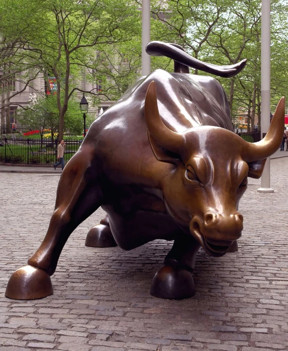 large bronze statue of an ox, on a brick path in front of a building